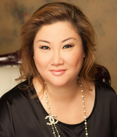A woman with shoulder-length hair, wearing a black top and a pearl necklace with a logo charm from Josephine's Day Spa, is seated against a neutral background.