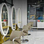 25-0190-InteriorHeader-P3-RiceVillage Nestled in the heart of Rice Village, this modern hair salon boasts circular mirrors, beige chairs, and light wood tables arranged in a sleek, white interior. | Josephine's Salons and Spas