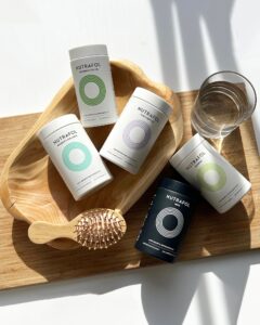 Nutrafol supplements, luxury hairbrush, water glass, and tray on wood at top Houston Aveda salon—ideal for healthy hair growth. | Josephine's Salons and Spas | Houston, TX