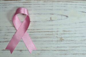 A pink ribbon loop on light wood, symbolizing breast cancer awareness and hair loss prevention at a luxury Aveda salon Houston, TX. | Josephine's Salons and Spas | Houston, TX